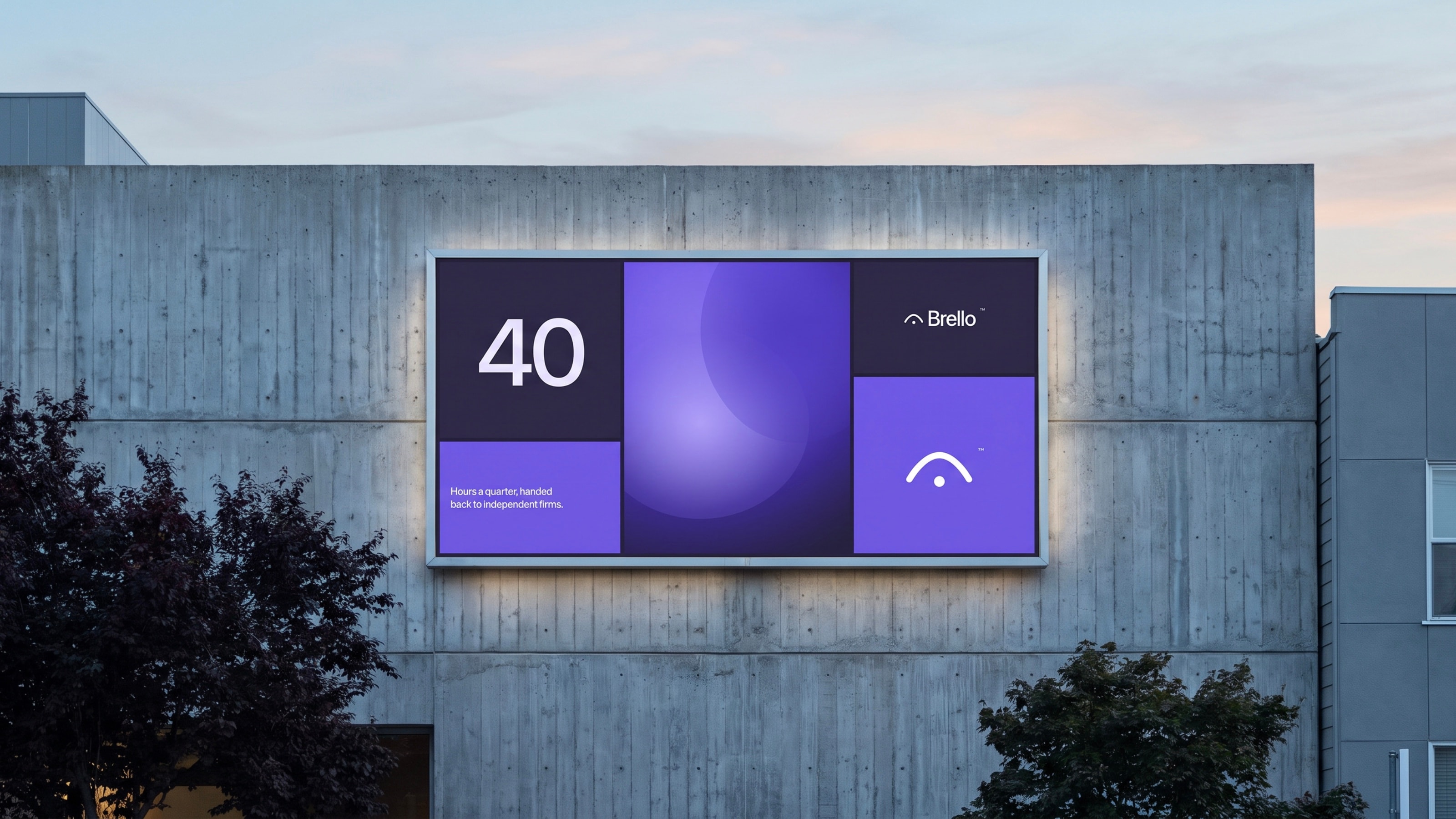 A lit Brello billboard on a concrete building at dusk, its violet and indigo panels carrying the canopy mark.